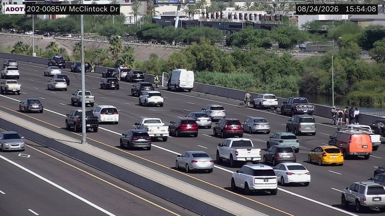 Two police vehicles and several individuals on the right shoulder