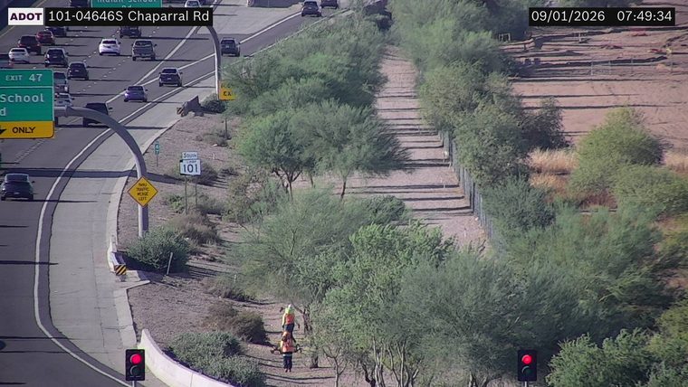 Two workers in high-visibility vests on the side of the road