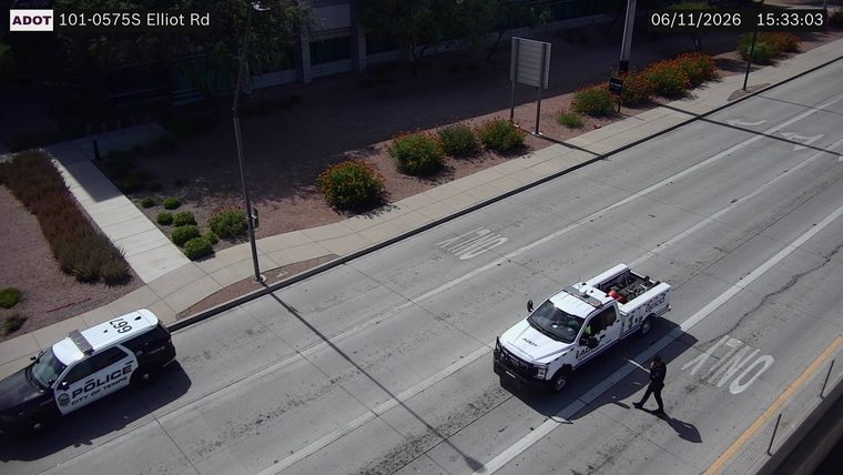 Police car and a tow truck with a person walking near them in the right lane