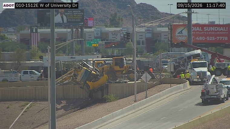 Tractor-trailer overturned with its trailer on top of the cab, and construction equipment in the median