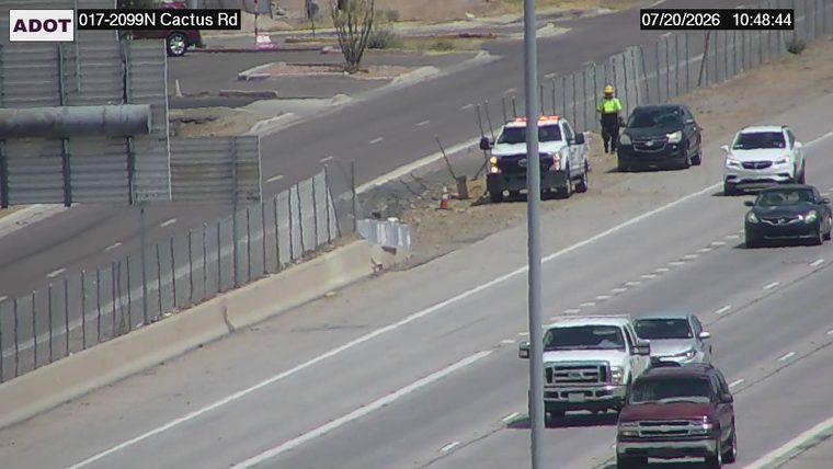 Worker in high-visibility vest and a service truck with orange lights on the shoulder
