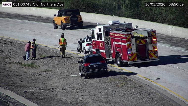 Phoenix Fire Department truck with emergency lights on, attending to a white car on the right shoulder