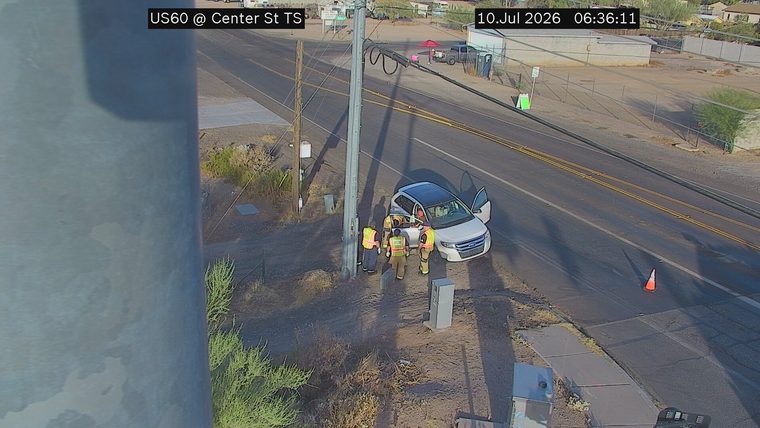 Three individuals in high-visibility vests near a white SUV with doors open, on the right shoulder.