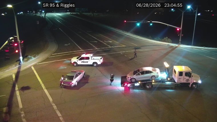 Police vehicle and tow truck with a car on its flatbed at an intersection