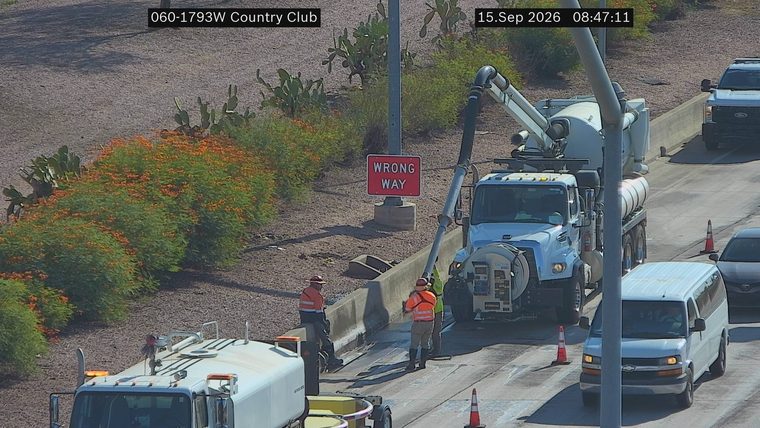 Workers and equipment on the roadway with a 'WRONG WAY' sign visible