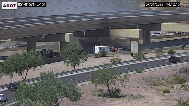 RV on fire with smoke and flames, with a fire truck and another vehicle present