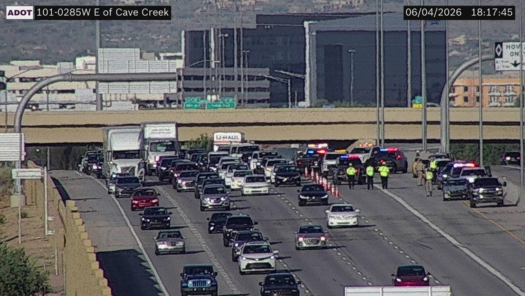 Multiple police cars and several individuals in high-visibility vests in the right lanes