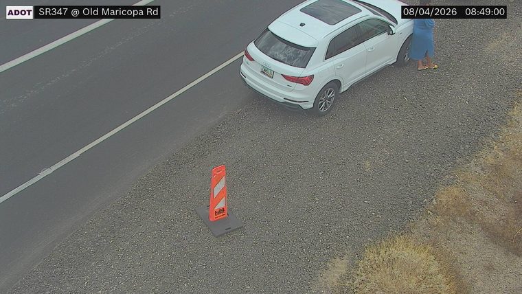 White SUV on the right shoulder with a person standing next to it