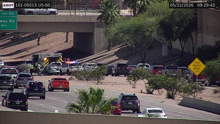 Police vehicle with flashing lights and an emergency rescue vehicle with responders on the left shoulder/exit ramp area