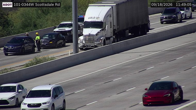 Two vehicles collided in the left lane, with a police car and a tow truck present