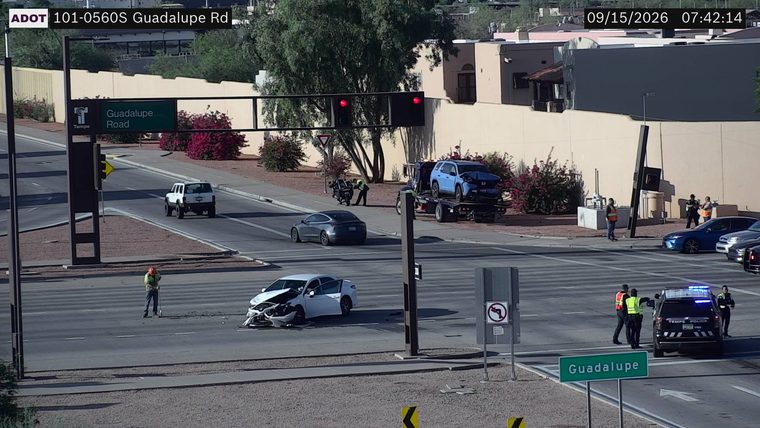 Two vehicles collided in the intersection, one with visible front-end damage and an open door, and a police car with lights on