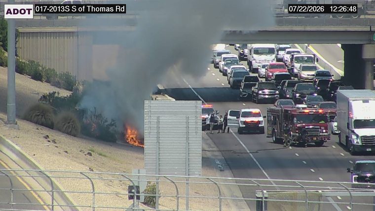 Fire and smoke on the embankment to the left of the roadway, with emergency responders present