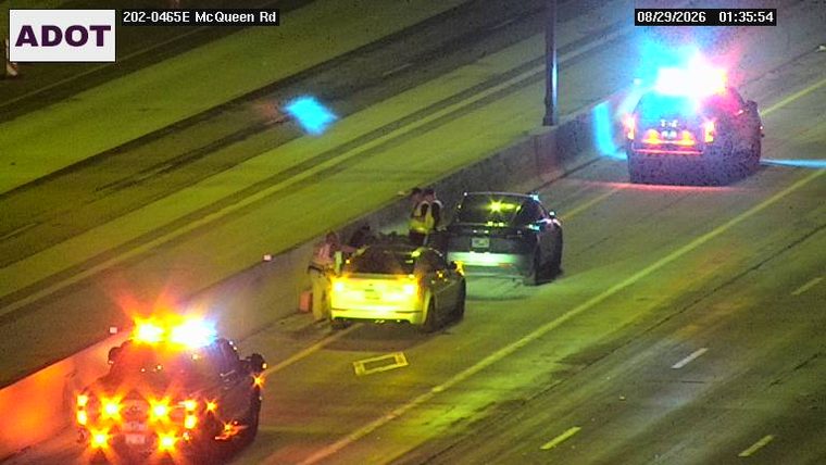Police car with red and blue lights on the right shoulder, attending to two vehicles in the travel lanes