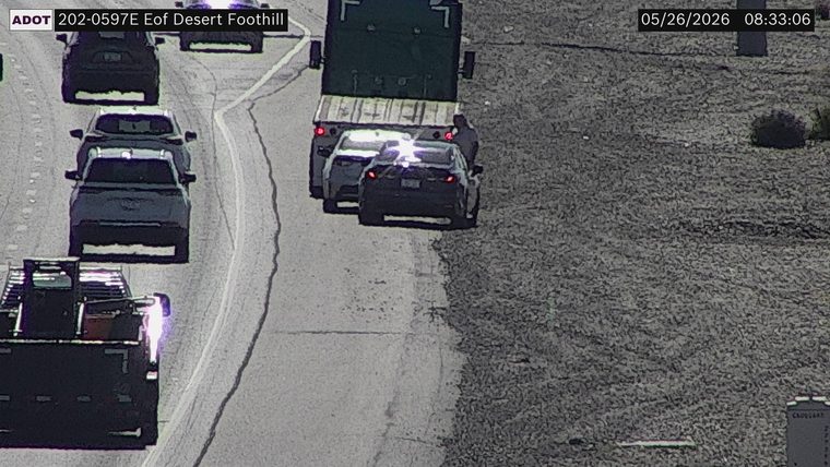 Two sedans and a truck stopped on the right shoulder with a person standing outside