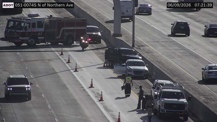 Fire truck and motorcycle on the left shoulder, with cones and people attending to a silver sedan and a dark SUV in the travel lanes