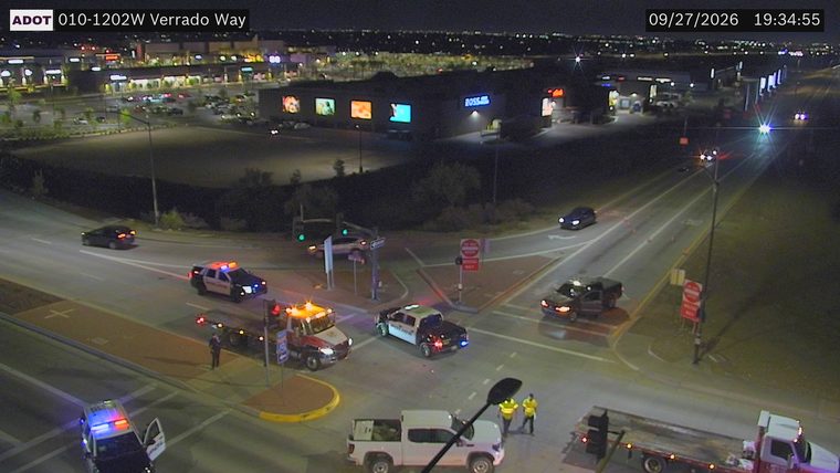 Two police cars with lights on and a tow truck at an intersection