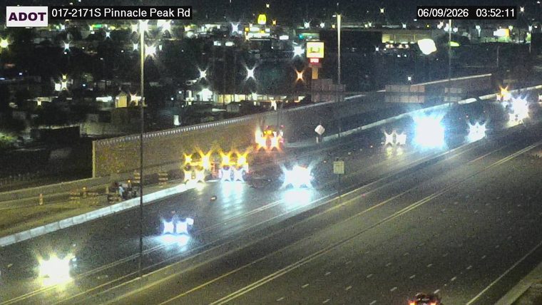 Multiple vehicles with flashing lights and cones in the left lanes
