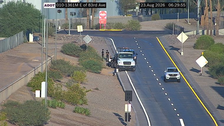 Tow truck and two individuals on the right shoulder