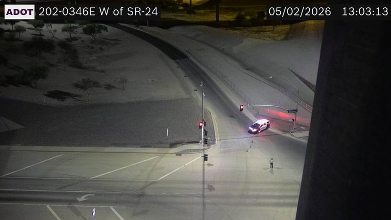 Police car with lights on and a person standing in the roadway