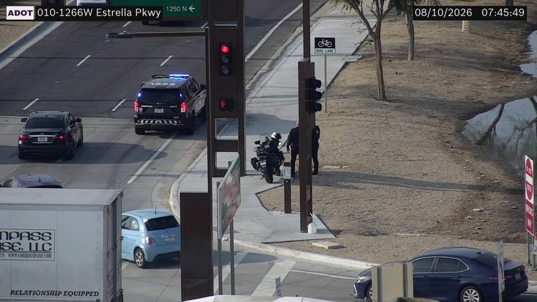 Police officers and a motorcycle on the sidewalk next to a traffic signal