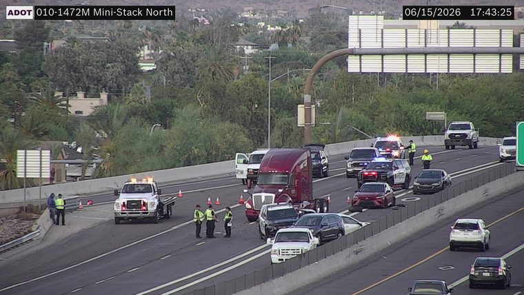 Multiple police vehicles and personnel on the roadway near a semi-truck and other vehicles