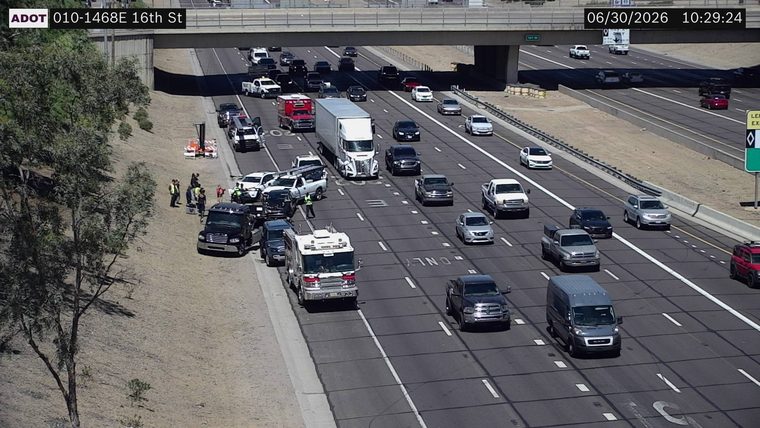 Several vehicles and people on the left shoulder and in the left lane
