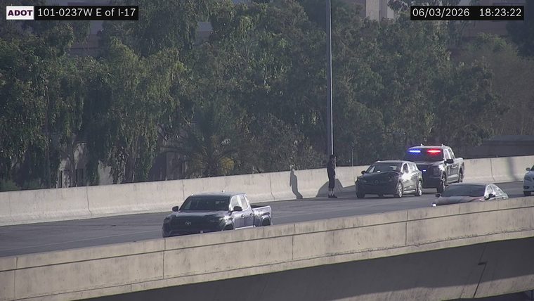 Police vehicle with lights on and a person standing next to it in the right lane