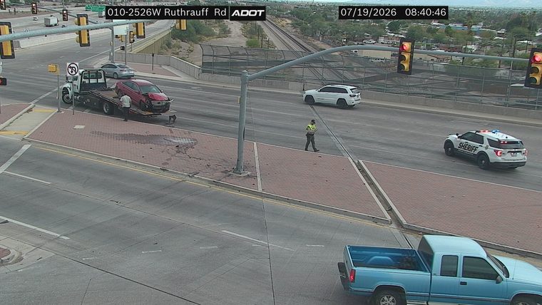 Tow truck with damaged red car on its flatbed, sheriff vehicle present