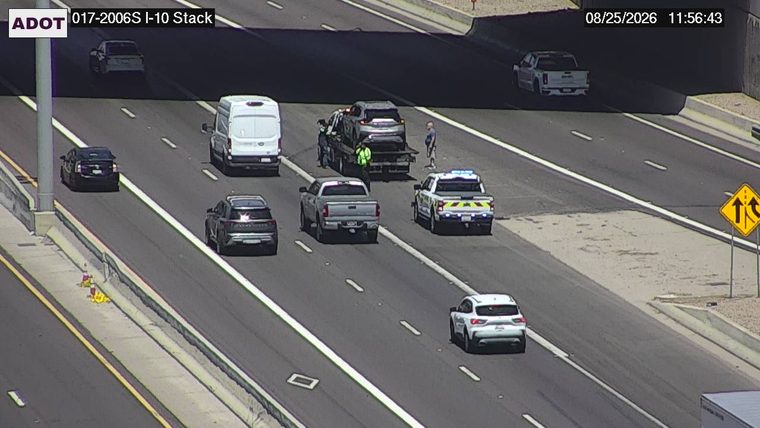 Tow truck with a car on it and a police vehicle with lights on in the right lane