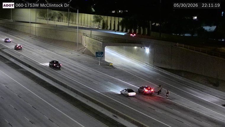 Multiple emergency vehicles with lights on and several people in the roadway