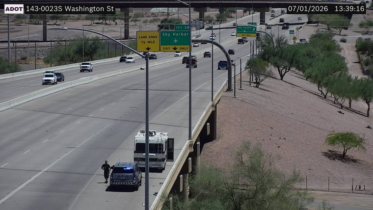 Police car with blue lights on the right shoulder next to an RV with an open door