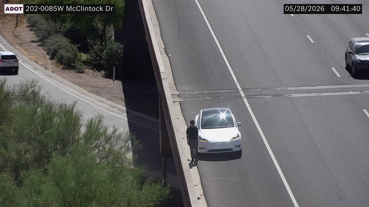 Person standing on the left shoulder next to a white car