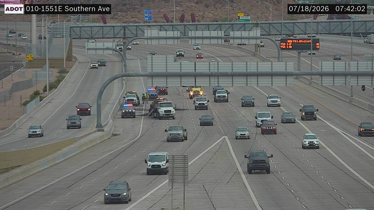 Police car and tow truck with emergency lights on in the left lanes