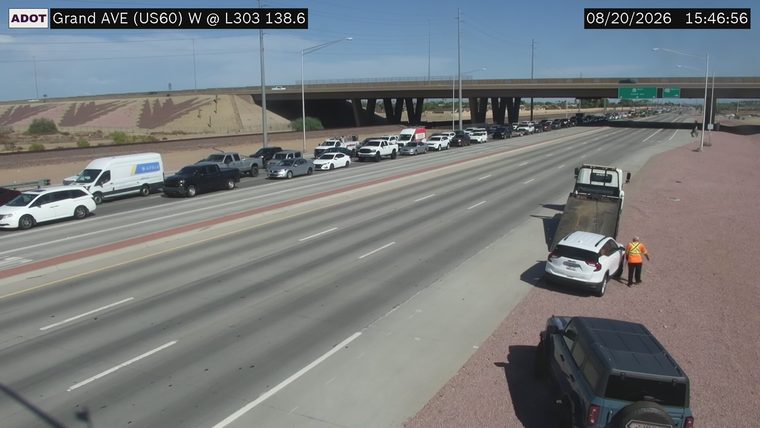 Person in high-visibility vest near white SUV on the shoulder