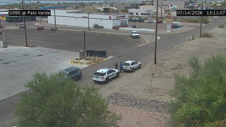 Police car with two officers and a civilian standing near a white SUV