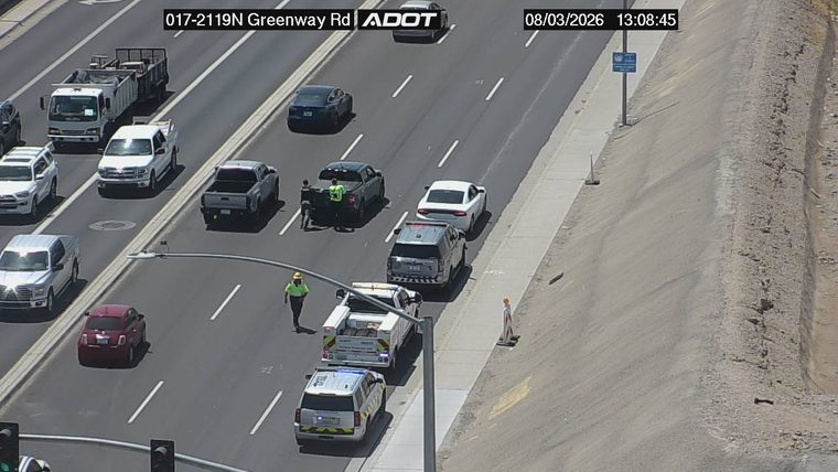 Two persons in high-visibility vests and a tow truck in the right lane