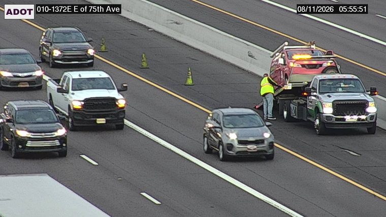 Tow truck with a vehicle on its bed and a worker in a hi-vis vest