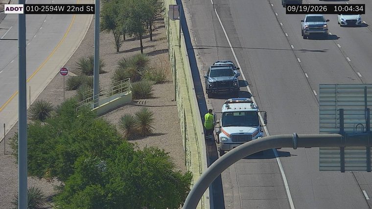 Tow truck and a person in a high-visibility vest on the right shoulder