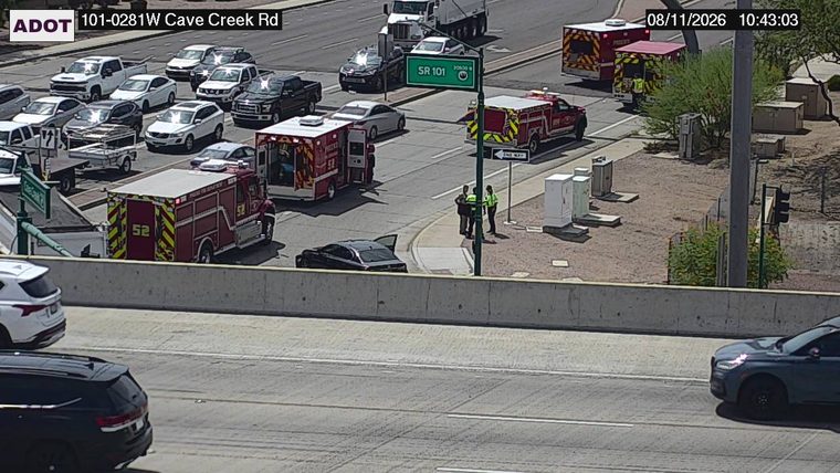 Two fire department vehicles and two individuals in high-visibility vests on the side of the road
