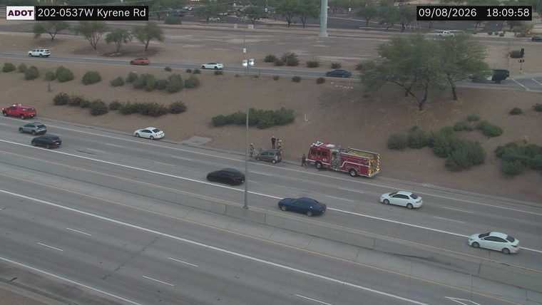 Fire truck and several people attending to a car on the right shoulder