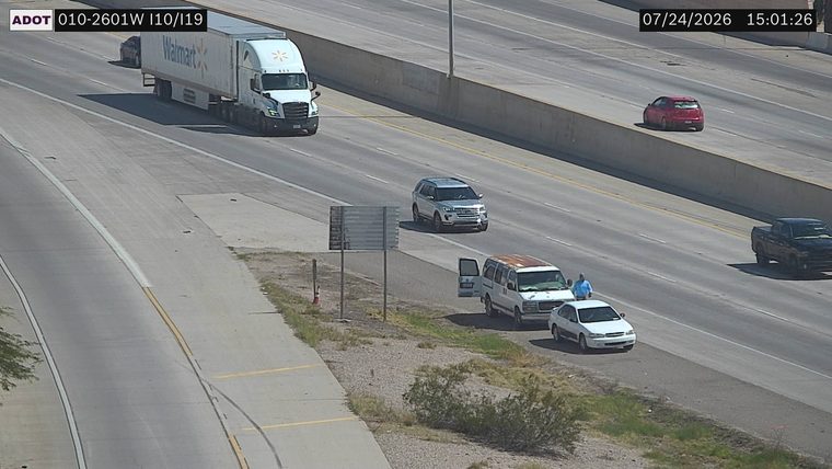 White van and white sedan on the right shoulder with a person standing between them