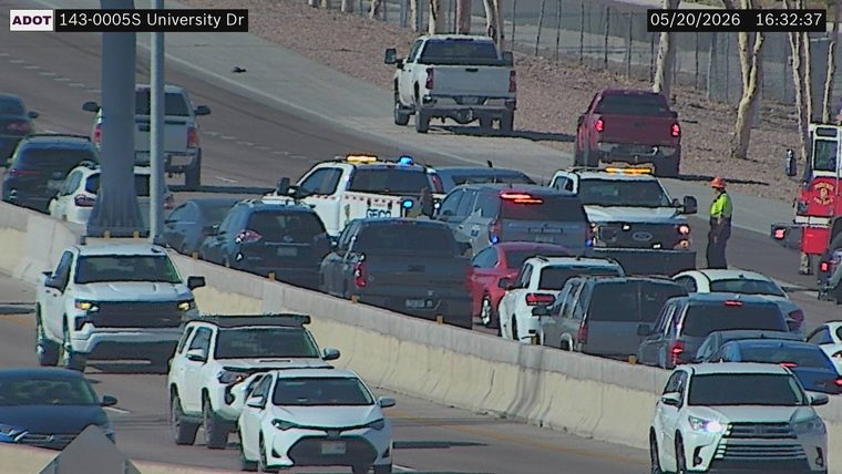 Emergency responders, including a service patrol vehicle with flashing lights, a fire truck, and a worker in a high-visibility vest, are active on the right side of the highway.