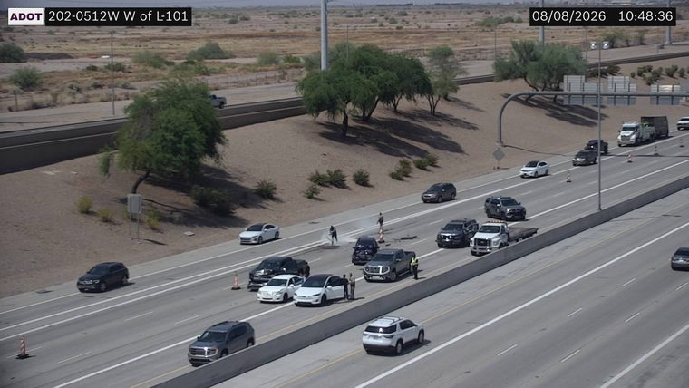 Two vehicles collided in the left lanes, with debris on the roadway and two individuals standing near the wreckage.