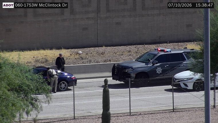 State Trooper vehicle with red and blue lights on the shoulder next to a stopped car