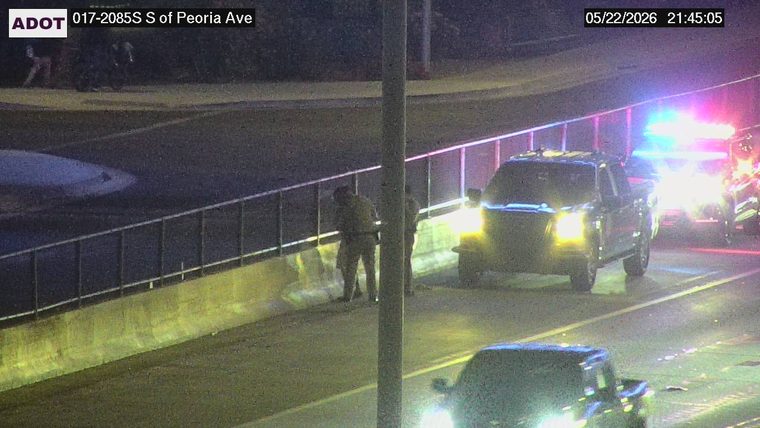 Police car with flashing lights and officers standing next to a pickup truck on the right shoulder