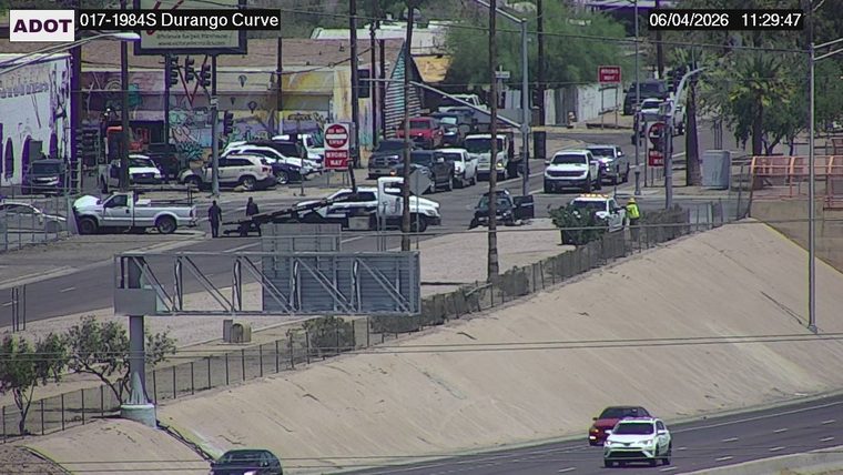 Tow truck and two individuals near a white pickup truck in the left lane