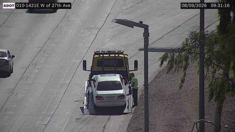 Tow truck assisting a white sedan on the right shoulder