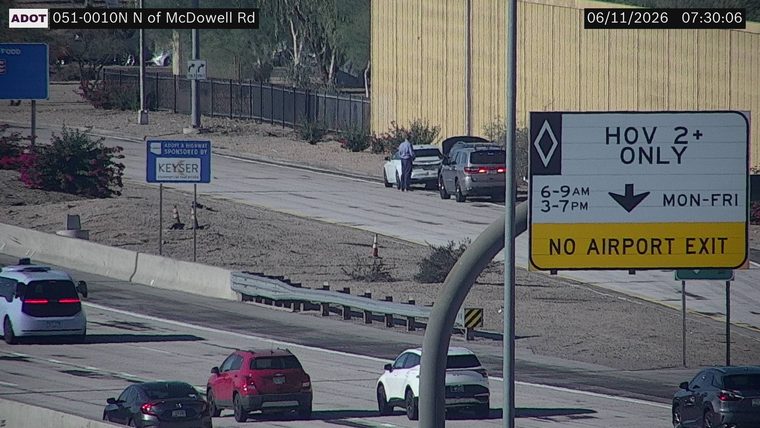 Person standing between two vehicles on the shoulder