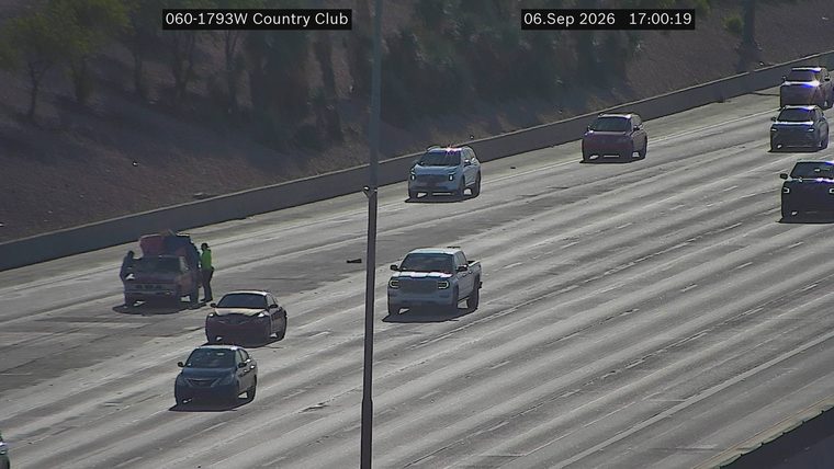 Two people attending to a red pickup truck in the left lane