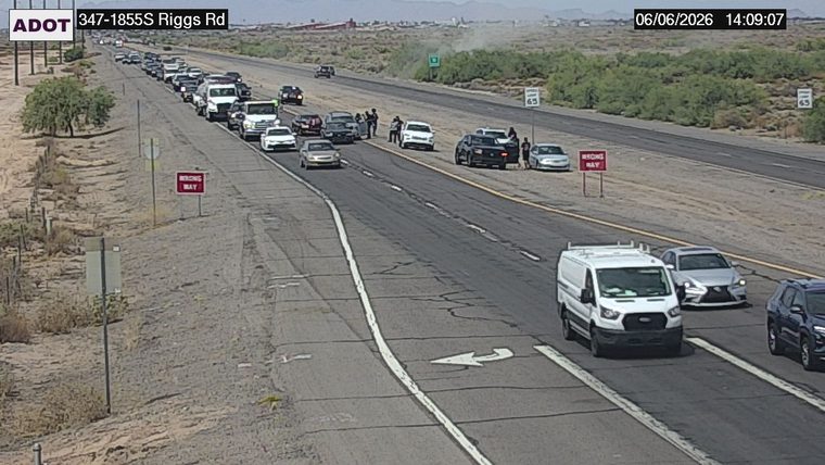 Several people standing around multiple vehicles in the left lane
